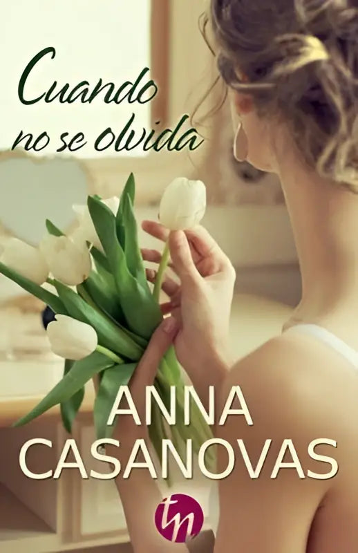 Een vrouw houdt een boek met de titel Cuando no se olvida en een boeket witte tulpen met groene stelen vast