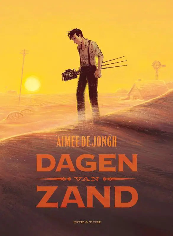 Een man in een lichtkleurig overhemd en donkere broek staat op een woestijnweg bij zonsondergang met een oude camera in dagen van zand