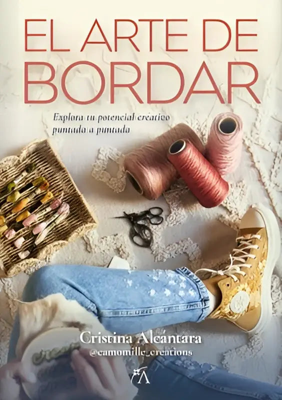De voorkant van este libro el arte de bordar met rode titel en mand met borduurmaterialen naast gele sneakers