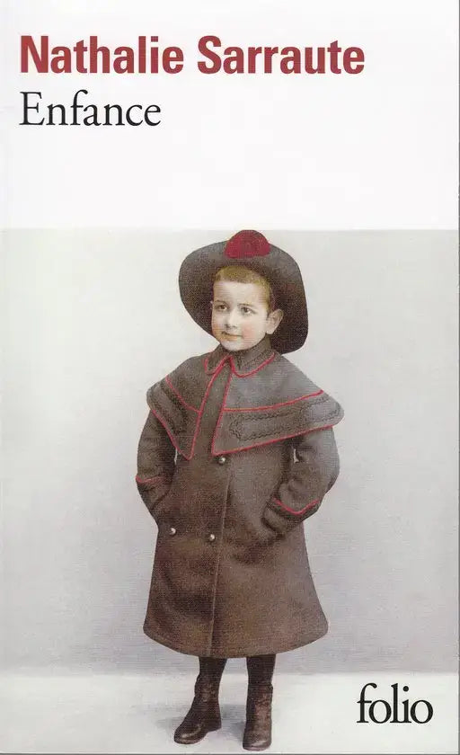 Een jonge jongen in een donkerbruine dubbele rij jas met rode bies en bijpassende hoed uit enfance collectie