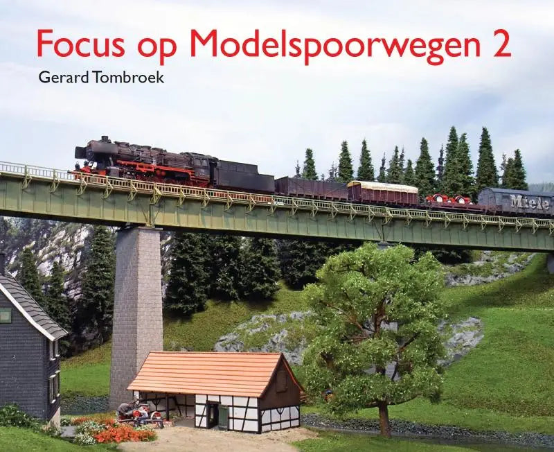 Een gedetailleerde model stoomlocomotief in zwart en rood trekt goederenwagens over een groen verhoogd spoorbrug in focus op modelspoorwegen