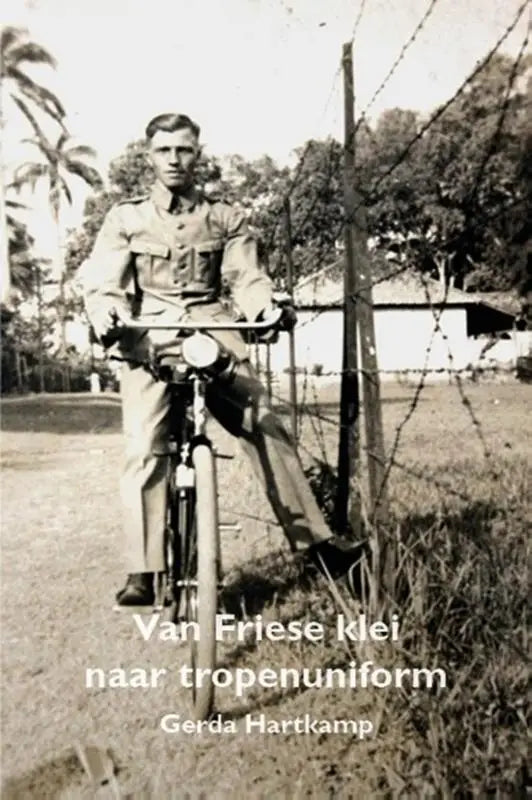 Vintage zwart-witfoto van een man in tropenuniform naast prikkeldraad met friese klei en tweede wereldoorlog thema