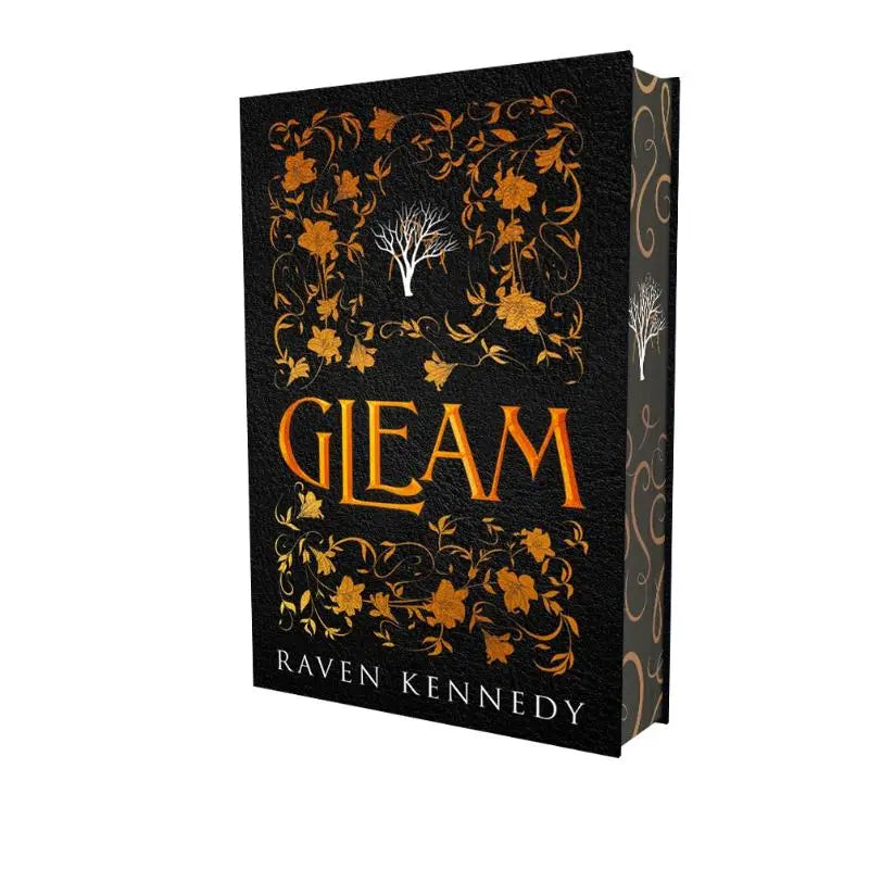 Zwarte hardcover boek gleam met gouden bloem- en boomontwerpen en oranje titel van raven kennedy, gouden gevangene editie