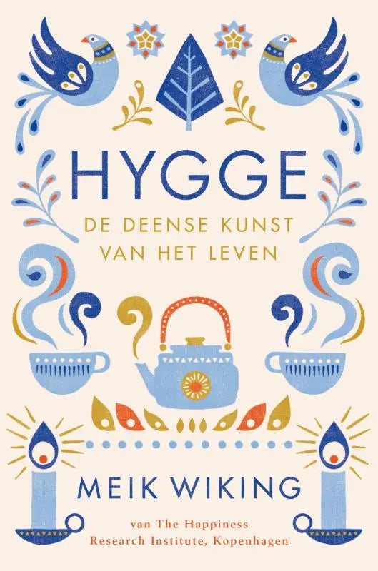 De cover van hygge de deense kunst van het leven toont blauwe en gouden vogels met theepotten en kaarsen op een lichte achtergrond