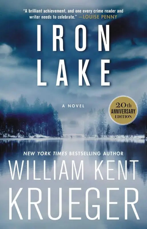 Boekcover van iron lake 20th anniversary edition door william kent krueger met blauw-wit sneeuwlandschap en weerspiegeling