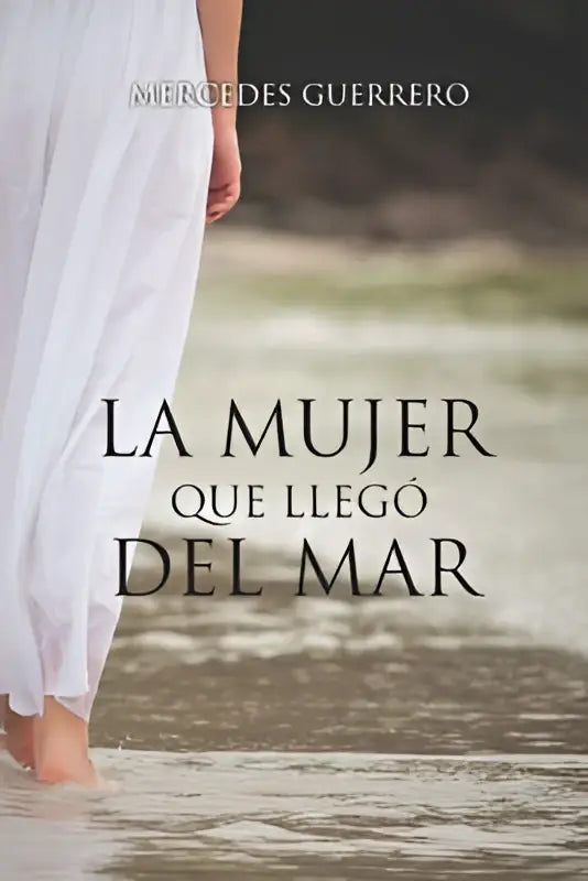 Een witte vloeiende jurk gedragen door een vrouw die staat in ondiep water in la mujer que llego del mar collectie