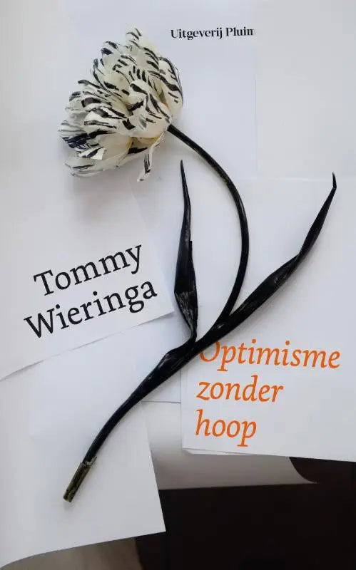 Een zwart wit papieren bloem met een delicaat gelaagd ontwerp op een open boek voor optimisme zonder hoop tommy wieringa uitgeverij pluim filosofie algemeen