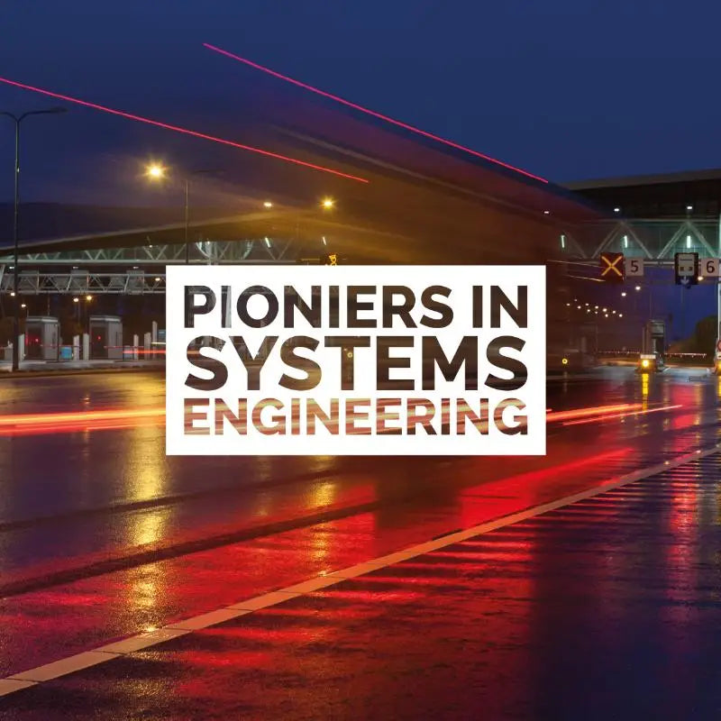 Wit rechthoekig bord met zwarte tekst pioniers in systems engineering tegen een natte weg in de nacht