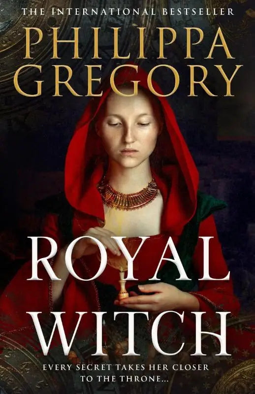 Red hooded figure with ornate gold necklace holding a small object on the cover of philippa gregory’s royal witch by harpercollins publishers