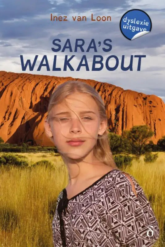 A young girl with blonde hair in a black and white geometric top stands before uluru in sara’s walkabout