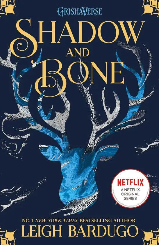 The shadow and bone book 1 cover shows a stylized stag head in blue and silver on a deep navy background