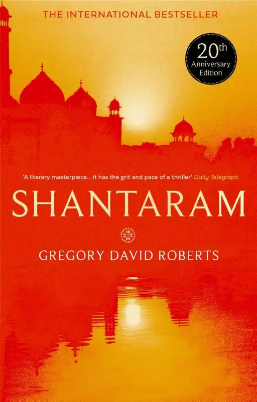 De paperback van de 20e jubileumeditie van shantaram met oranje en rode achtergrond als apple tv+ series starring charlie hunnam