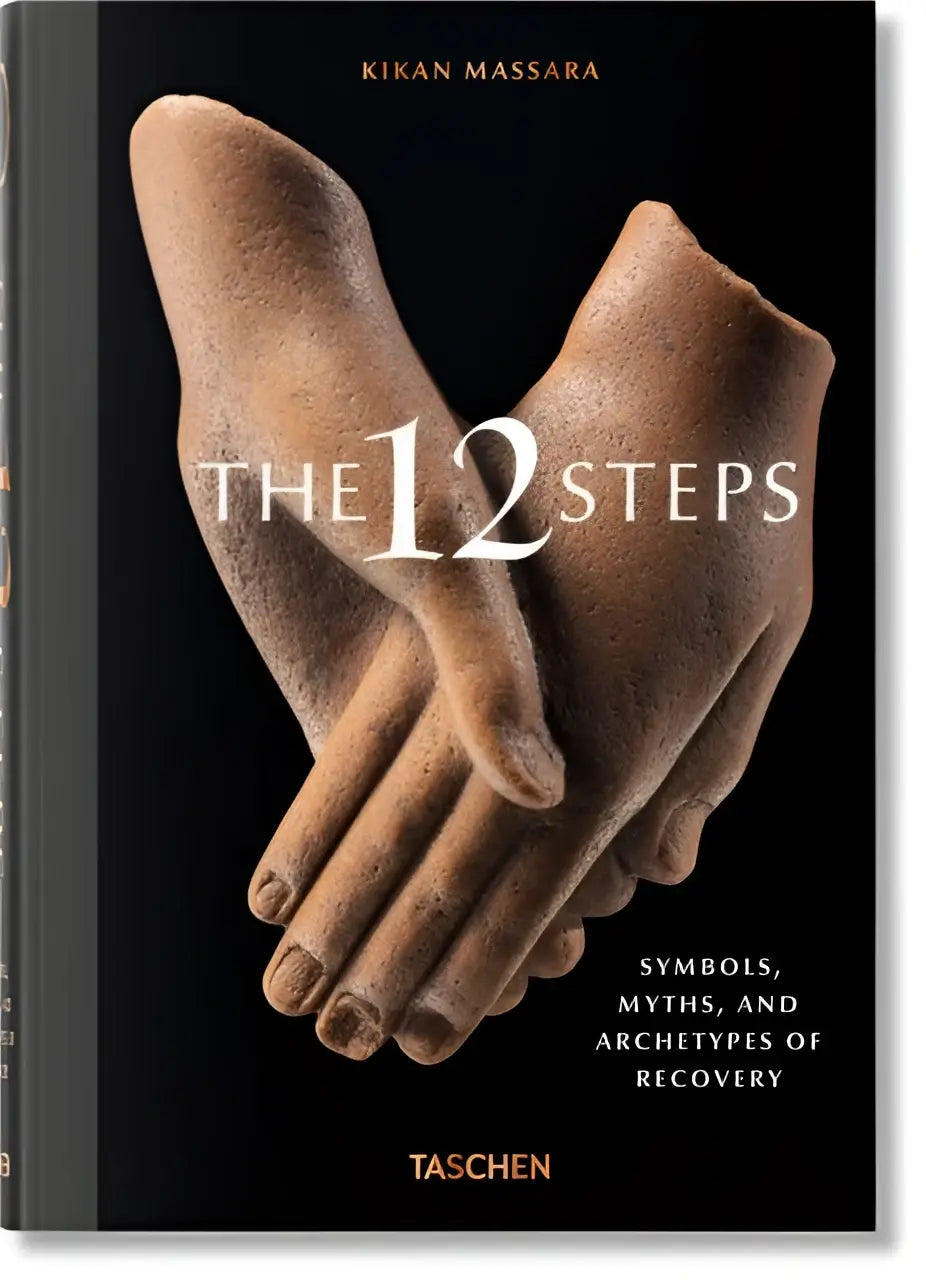 Black hardcover book the 12 steps by kikan massara with textured stone clasped hands sculpture featuring symbols and archetypes