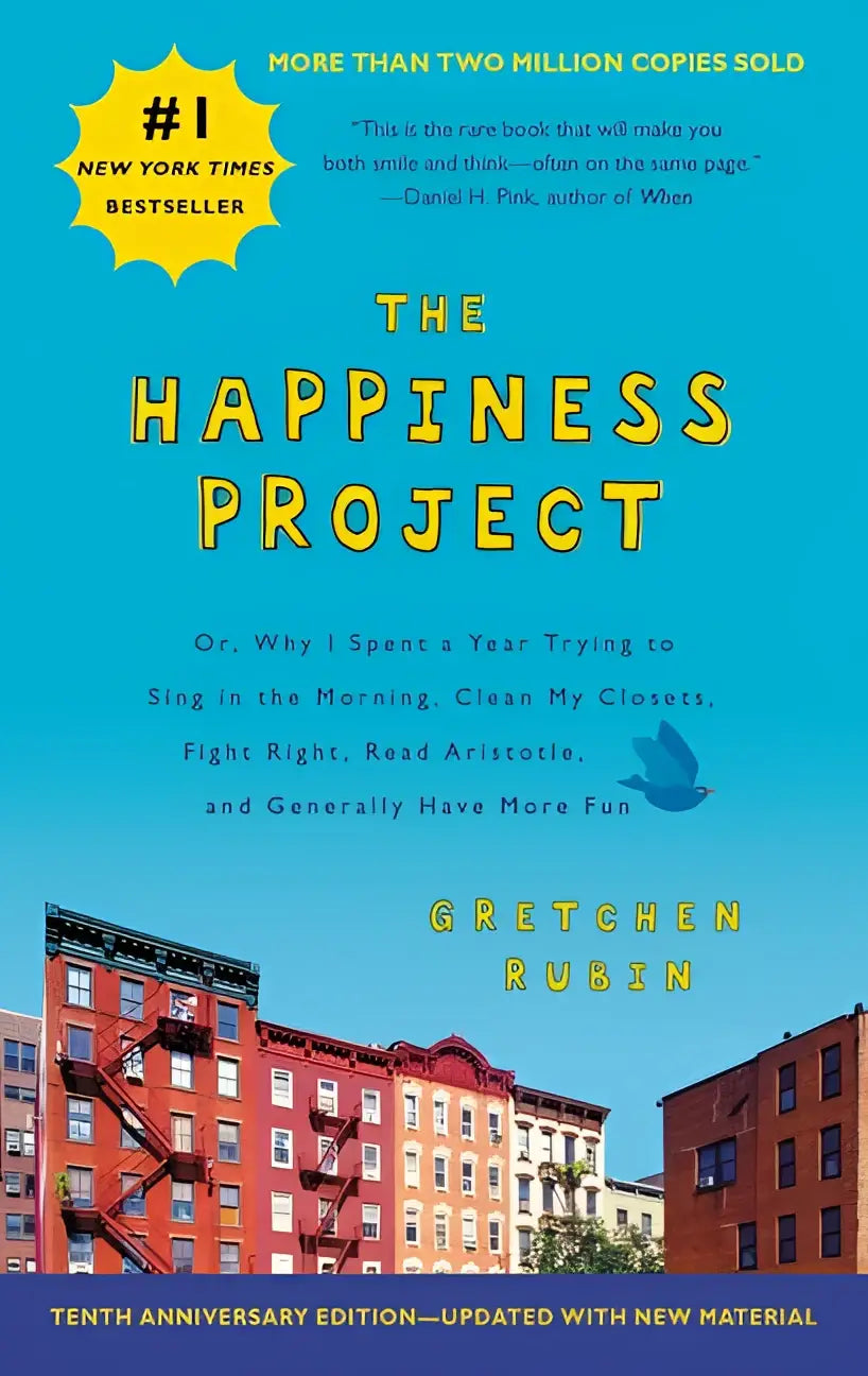 The happiness project tenth anniversary edition hardcover book in vibrant blue with yellow lettering and colorful brick building illustration