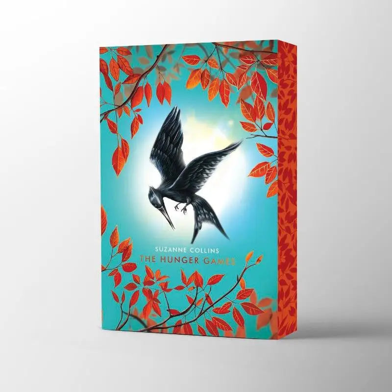 The hunger games deluxe boek door suzanne collins met zwarte vogel en oranje herfstbladeren voor jonge lezers