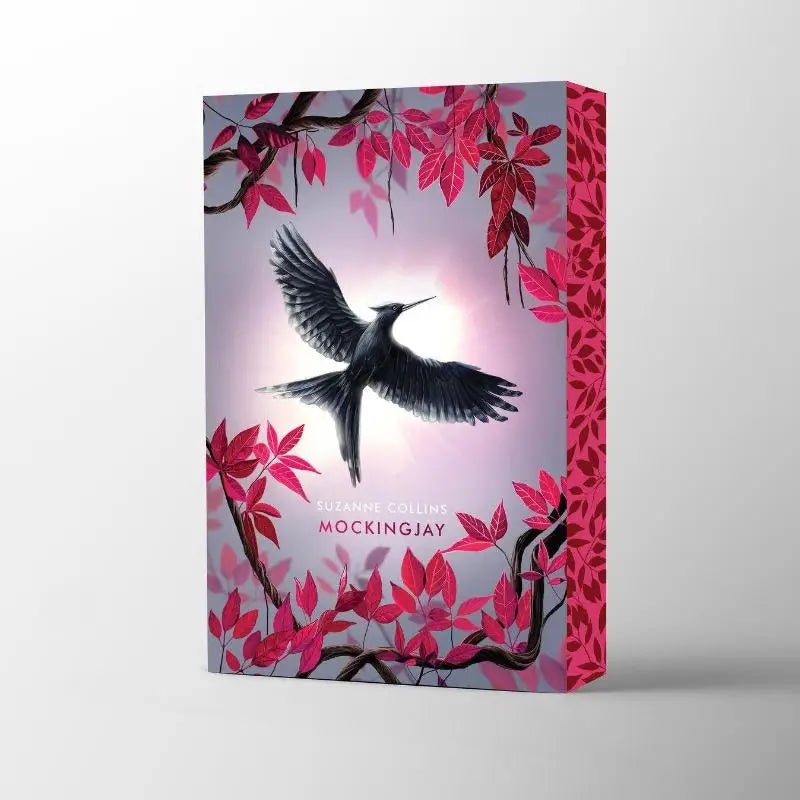 The hunger games mockingjay deluxe boekomslag met zwarte vogel en rode bladeren op zachte lila en roze achtergrond voor jonge lezers