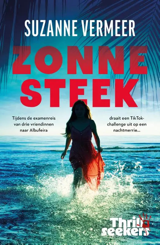 Vrouw in een vloeiende rode jurk van het product thrillseekers zonnesteek die door turquoise oceaan water wandelt