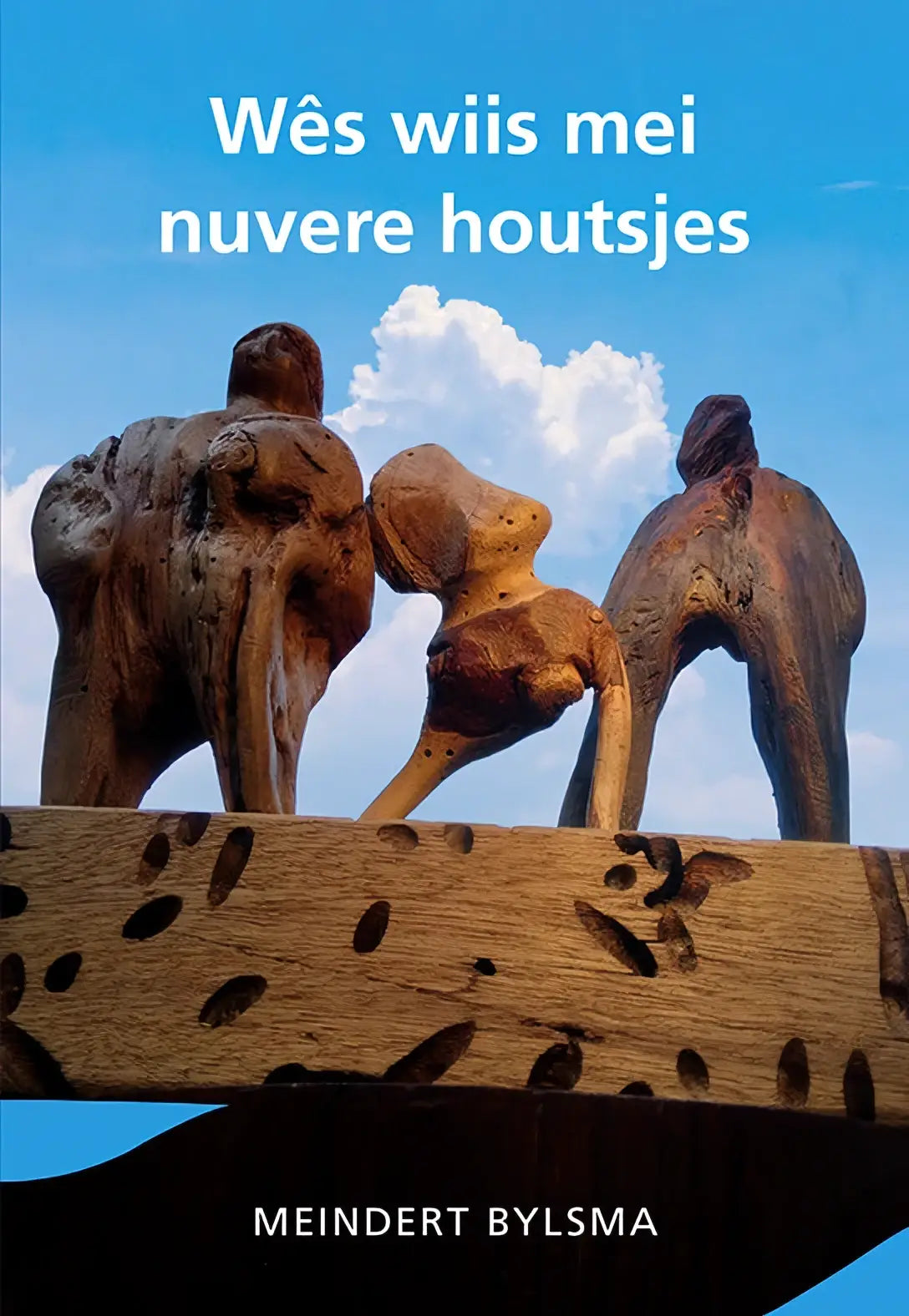 Drie wiis mei nuvere houten sculpturen met natuurlijke verweerde texturen en aardse bruine tinten tegen blauwe lucht