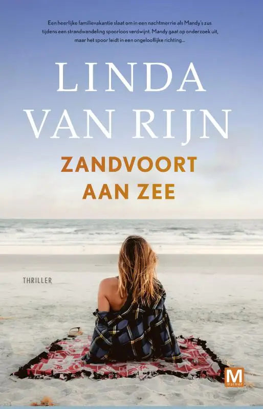 Een vrouw zit op het zandvoort aan zee strand met een donkerblauwe en zwarte geruite deken met rode en witte accenten