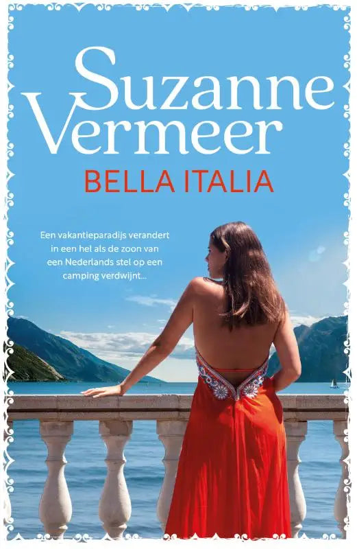 Vrouw in een rode jurk bella italia met geborduurde rugdetails bij een balustrade met uitzicht op bergen