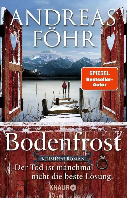 Rode houten bodenfrost poort met hartvormige uitsparingen die een besneeuwd meer omlijsten