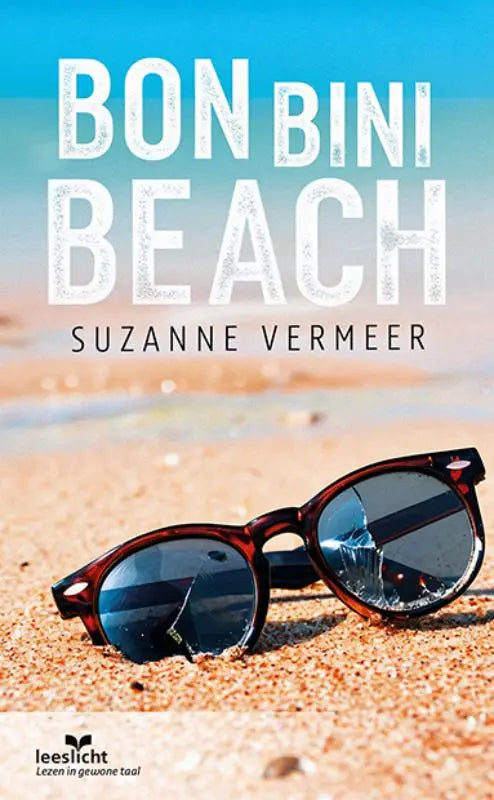 A pair of tortoiseshell-framed bon bini beach sunglasses with dark reflective lenses on a sandy beach