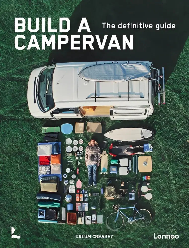 Witte camperbus met blauwe zeil op het dak omringd door kampeeruitrusting op gras in de definitieve gids