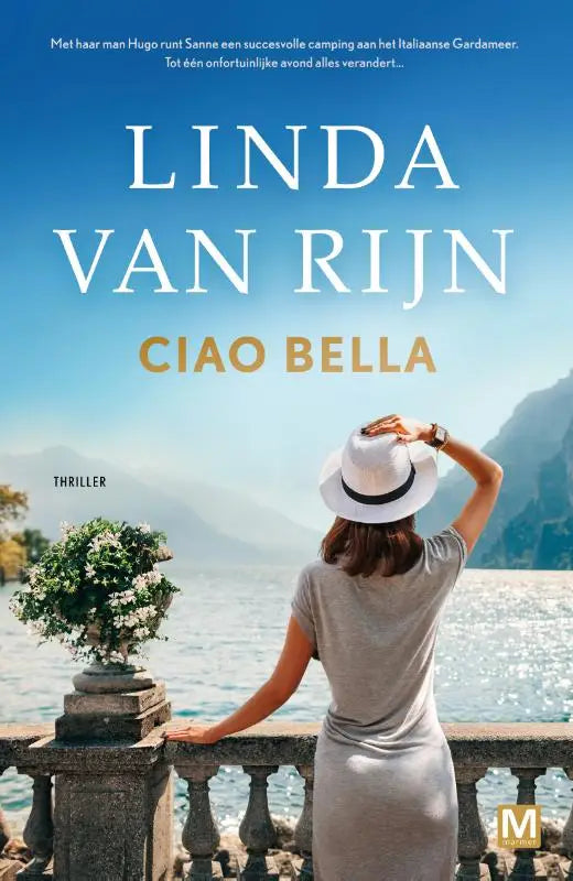 Een vrouw in een lichtgrijze jurk en een witte fedora met zwarte band staat op een stenen balkon ciao bella