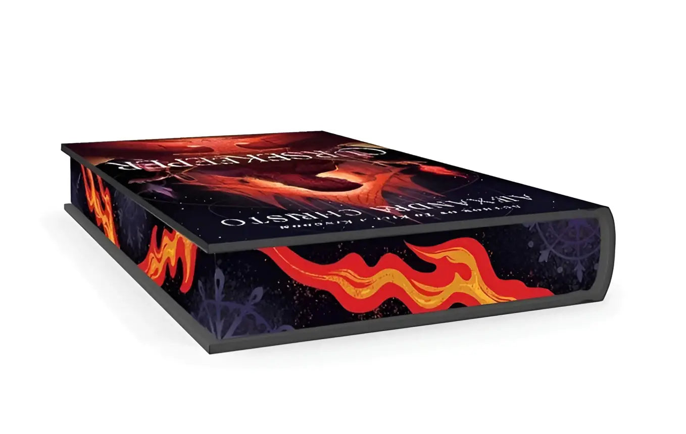 A hardcover cursekeeper deluxe edition book by alexandra christo with dark blue cover and orange flame design