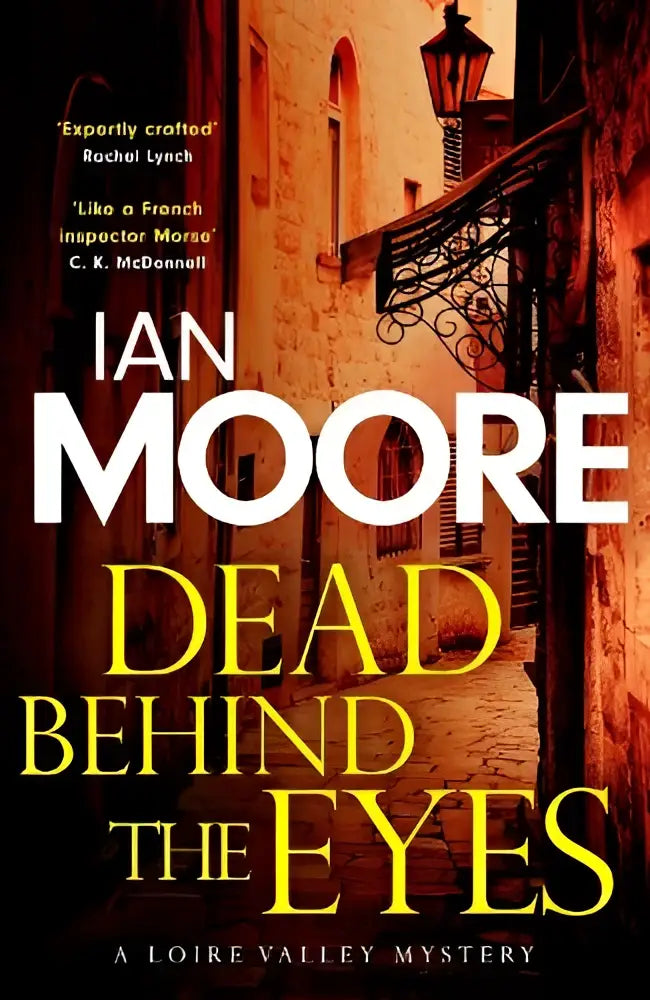 De cover van dead behind the eyes door ian moore toont een warm beeld van een oude straat in de loire valley voor een slickly plotted murder
