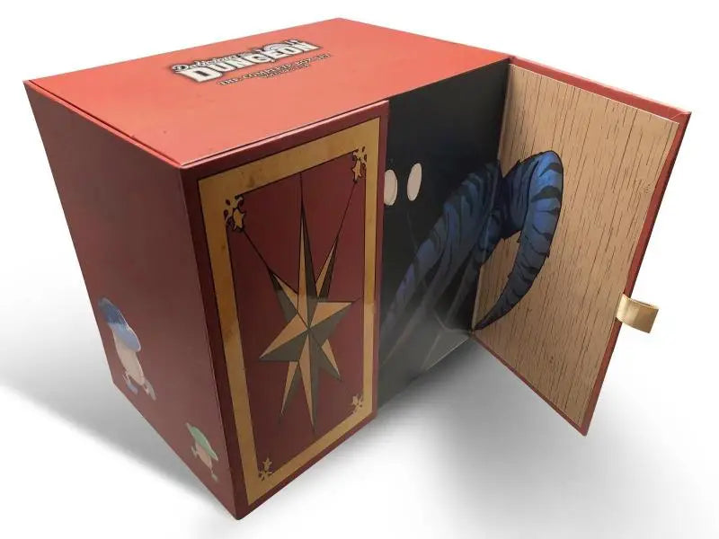 Rode kartonnen doos met goudgetrimde kaartontwerp en dungeons & dragons branding met blauwe draak in the complete box set of delicious in dungeon