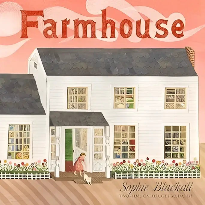 White farmhouse with black shingles and green front door surrounded by flower beds and white picket fence