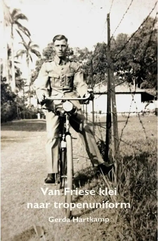 Vintage zwartwitfoto van een man in tropenuniform van tweede wereldoorlog zittend op een fiets tussen palmbomen en friese klei