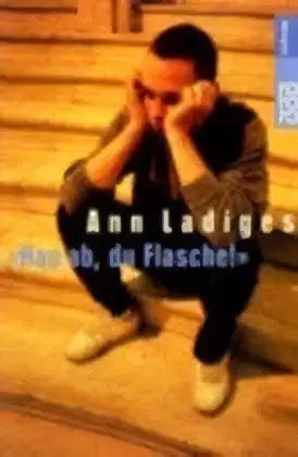 Een man in een donkere jas en broek zit op houten trappen met zijn handen voor zijn gezicht bij roland ouders product hau ab du flasche