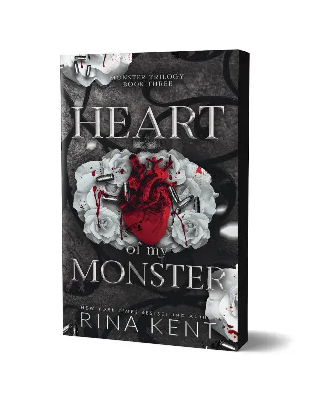 De boekomslag van heart of my monster deluxe edition door rina kent toont een rode hart omringd door witte rozen en kogels