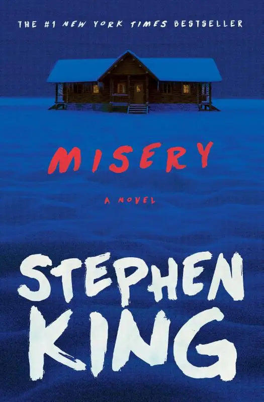 De boekcover van misery door stephen king toont een donkere houten cabine met verlichte ramen in een blauw besneeuwd landschap