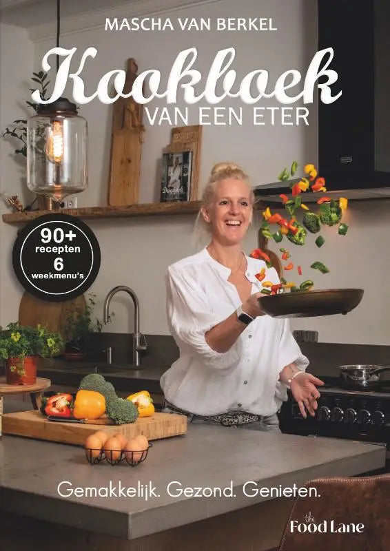 Een vrouw in wit houdt een donkere koekenpan met kleurrijke groenten in de keuken voor kookboek van een eter makkelijk gezond genieten