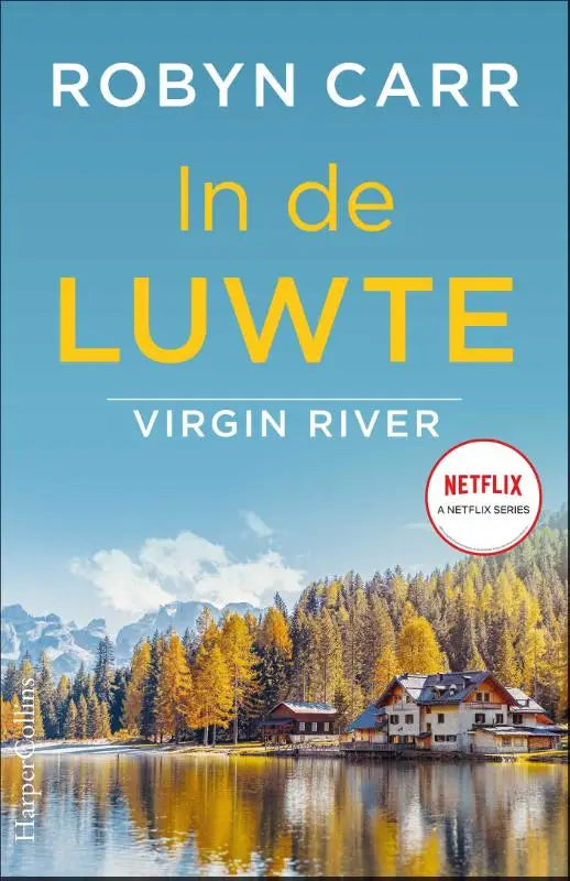 De boekcover van in de luwte toont een serene plas met herfstbomen en besneeuwde bergen onder een blauwe lucht