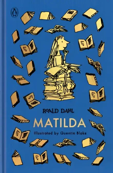Blauw gebonden roald dahl boek matilda met goudkleurige illustratie van matilda en zwevende boeken door quentin blake
