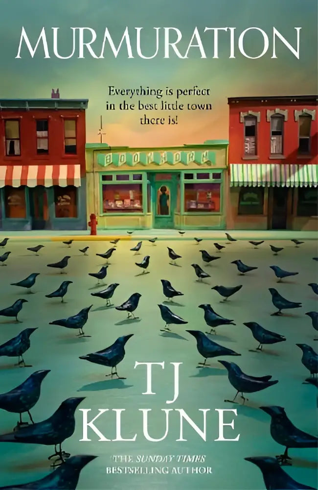 The book cover for murmuration by tj klune shows a quaint town with red and green storefronts surrounded by dark blue birds