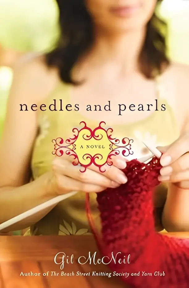 Een vrouw in een geel shirt houdt breinaalden en rood garen met het boek needles and pearls van Gil McNeil