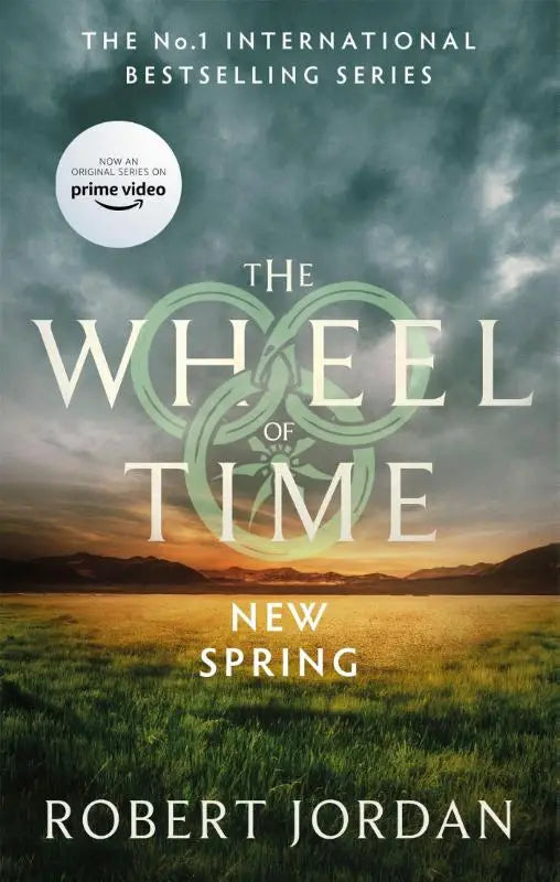 New spring a wheel of time prequel book cover with dramatic sky golden field and green wheel emblem now a major tv series