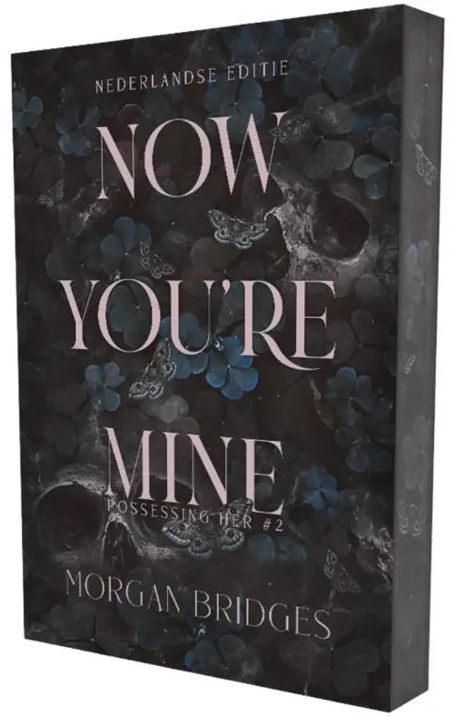 Donkergrijs boek met bloemen- en vlinderdessin en de titel now you’re mine van morgan bridges in witte serif lettertype