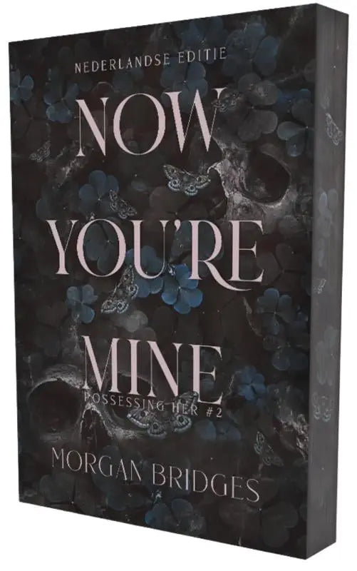 Donkere boekcover met zilveren tekst en blauwe bloemenpatronen van now youre mine door morgan bridges