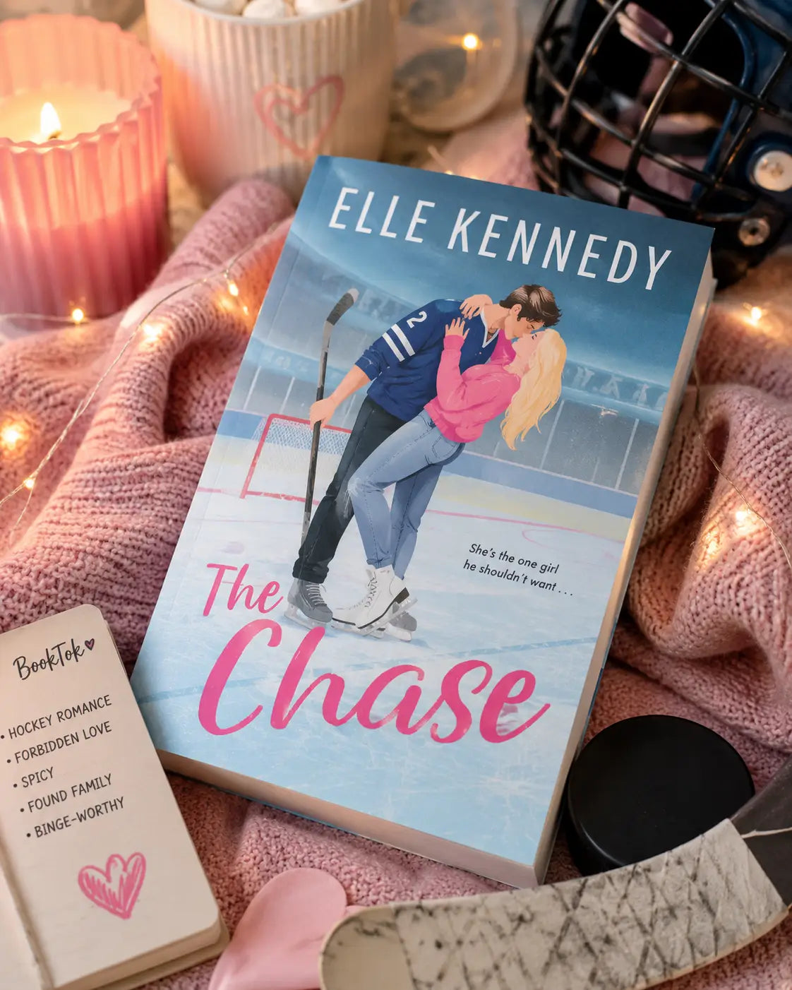 Paperback romance novel the chase by elle kennedy with a blue and pink cover featuring an illustrated hockey couple on ice