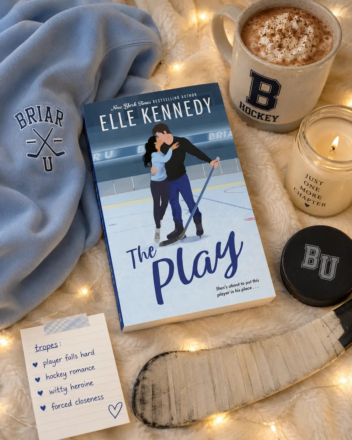 Blauwe en witte hardcover boek the play van elle kennedy met illustratie van schaatsers en hockeystick, off campus spin off