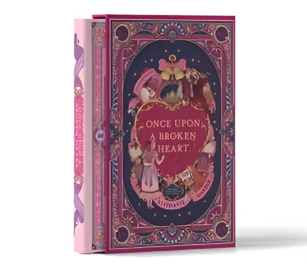 Een roze hardcover boek met een vintage stijl en illustraties getiteld once upon a broken heart collectors edition stenciled edge