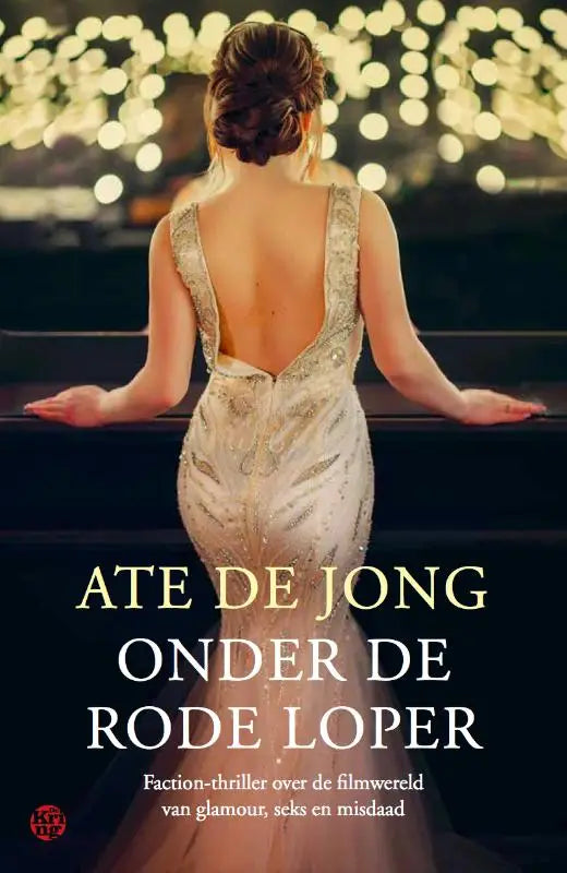 Een vrouw in een elegante, rugloze ivoorkleurige jurk met gouden borduurwerk staat bij een piano onder warme stringverlichting voor rode loper