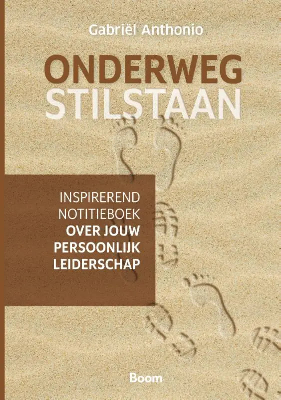 De boekcover van onderweg stilstaan door Gabriël Anthonio toont een inspirerend notieboek over persoonlijk leiderschap met een beige achtergrond en voetafdrukken in zand