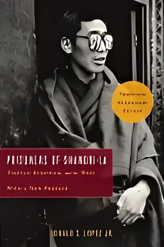 Een zwart-witfoto van een man met bril en donkere jas zittend bij het boek prisoners of shangri-la tibetaanse boeddhisme en het westen